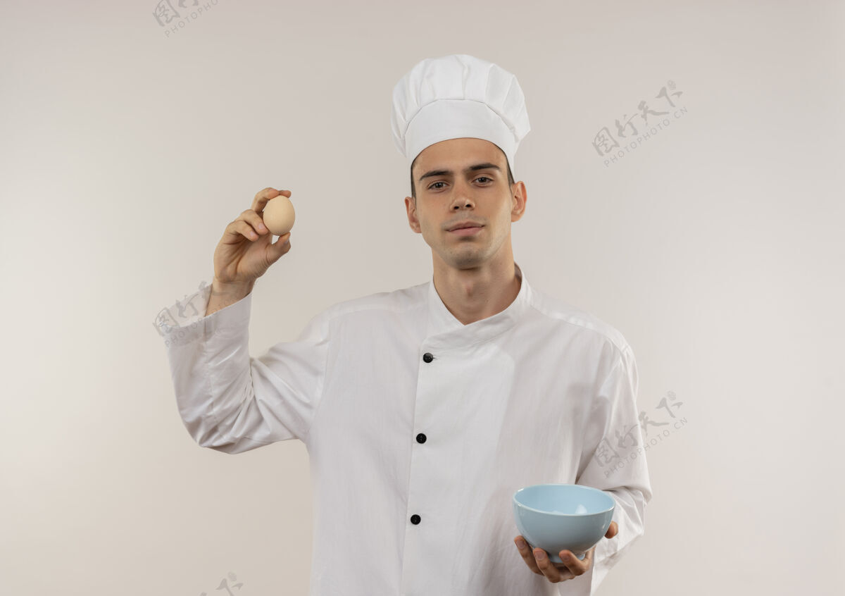 男性自信的年轻男厨师穿着厨师制服 在隔离的白色墙上拿着碗和鸡蛋年轻穿着持有