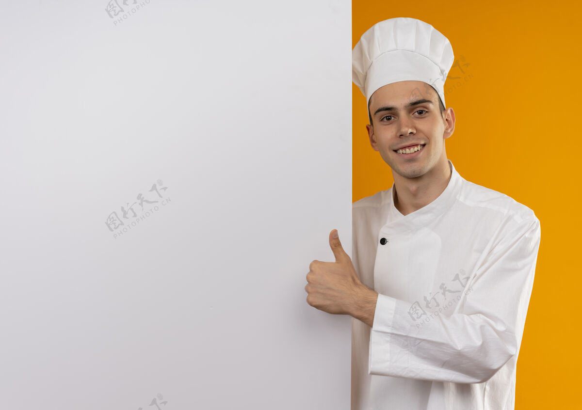 男笑容可掬的男青年酷酷地穿着厨师制服捧着白墙大拇指向上抄着空格制服拿着墙