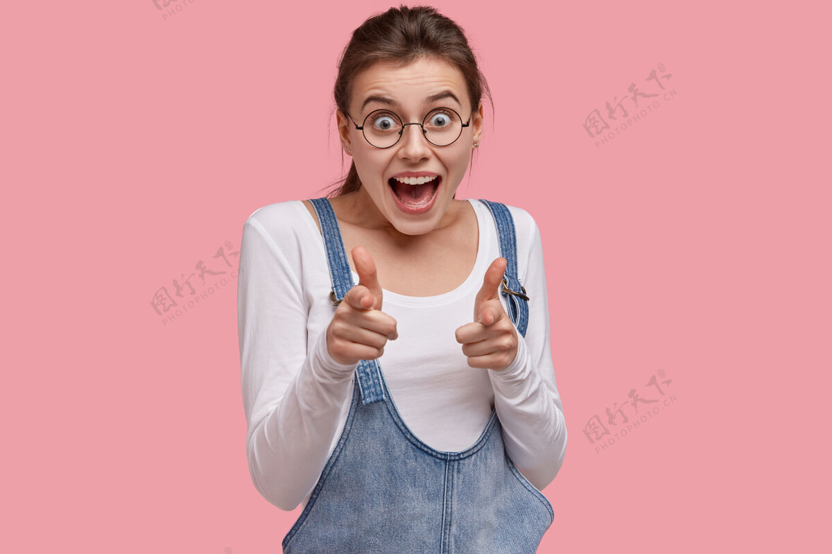 手照片中的快乐女人用手指指着镜头 表情欢快 笑得很兴奋展示选择工作服