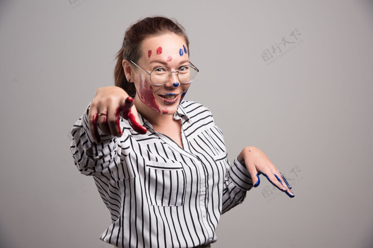 眼镜脸上涂着颜料 戴着灰色背景眼镜的女人手艺术家墨水