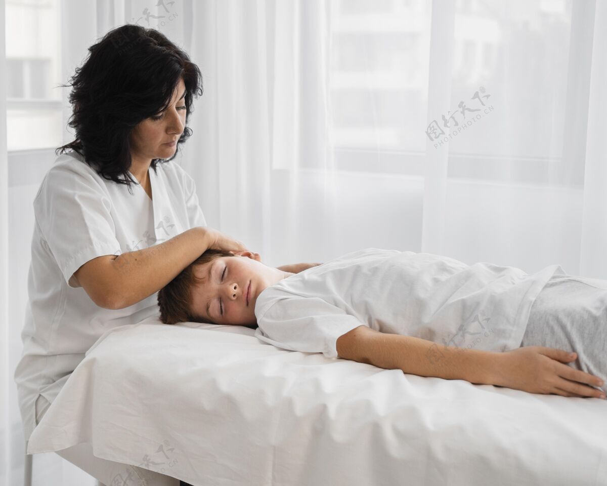 医疗女骨科医生在治疗一个男孩健康保健理疗