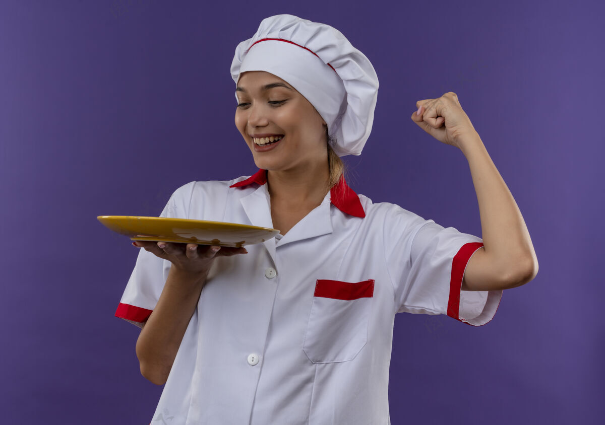 制服微笑的年轻厨师女 穿着厨师制服 拿着盘子 在有复印空间的孤立背景上显示“是”的手势盘子厨师手势