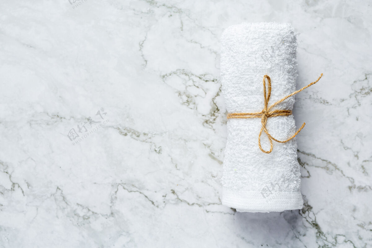 放松卷好的白色浴巾放在白色大理石地板上材料生活自然
