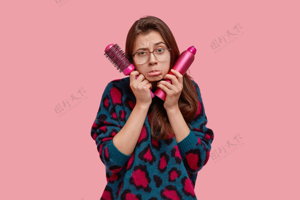 痛苦郁闷的欧洲女人孤注一掷端着发刷和喷雾 不满地掏着下唇发型发廊装束
