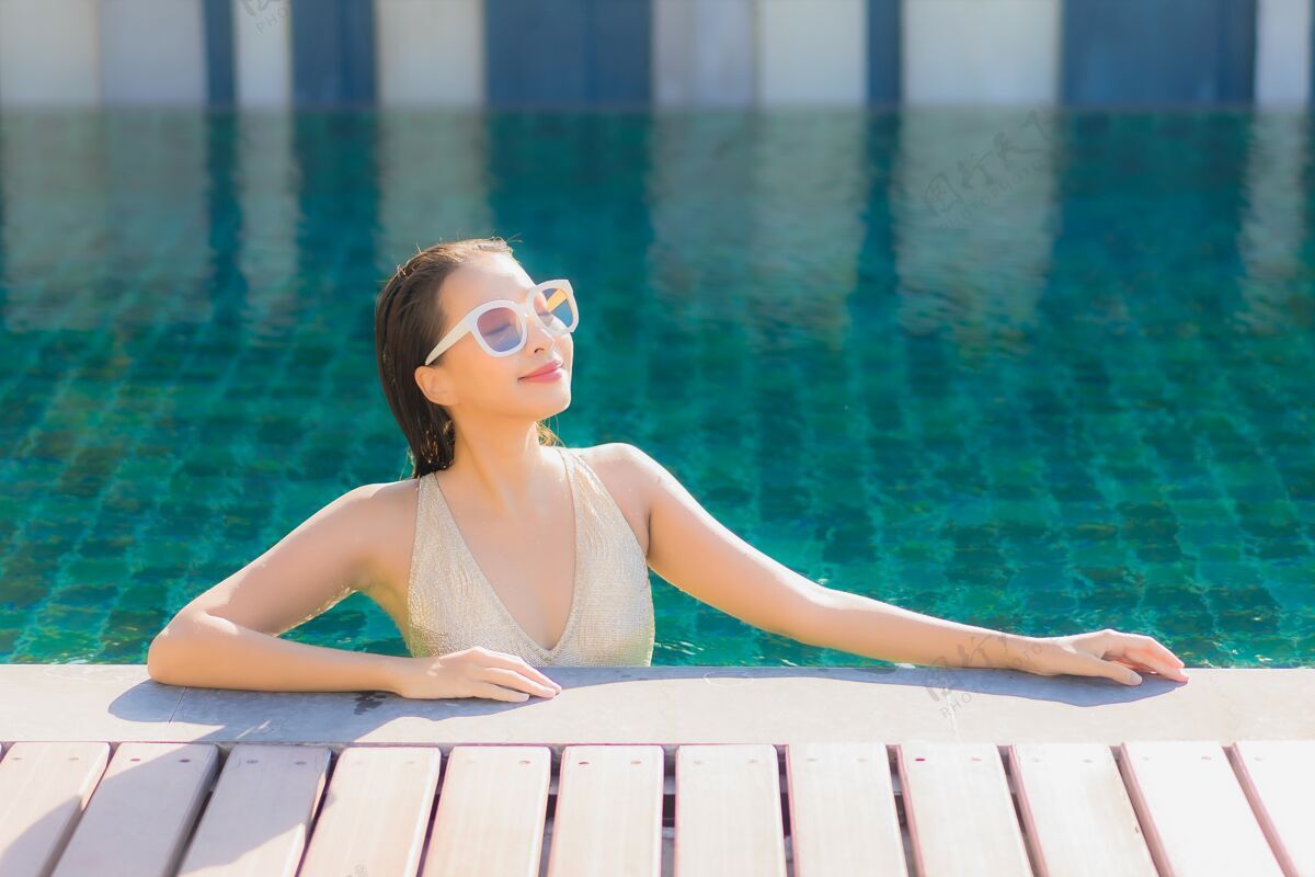 休闲美丽的亚洲年轻女子在度假酒店的室外游泳池周围放松的肖像游泳游泳泳装
