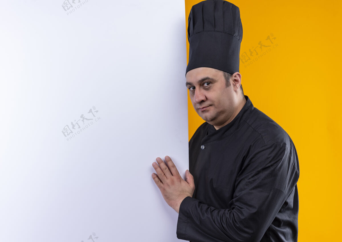 厨师身穿厨师制服的中年男厨师手拿白墙 黄墙上有临摹空间抱着看着厨师