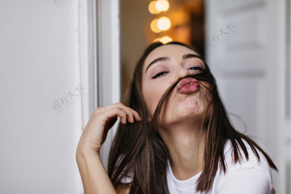 正面室内快乐女模特做鬼脸的写真嬉皮的棕色头发女士摆出亲吻表情的照片女士特写拍摄