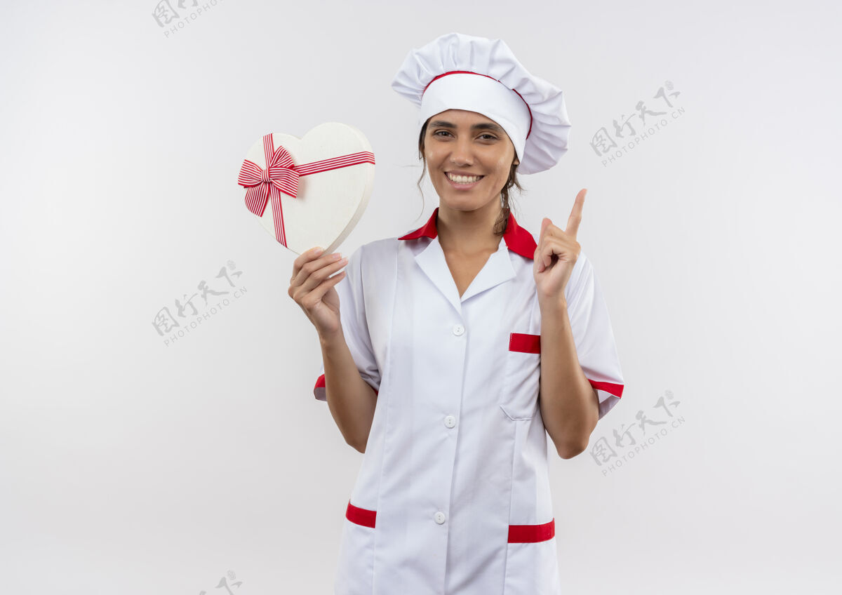 点面带微笑的年轻女厨师穿着厨师制服手持心形盒子 指着上面的复印空间女心制服