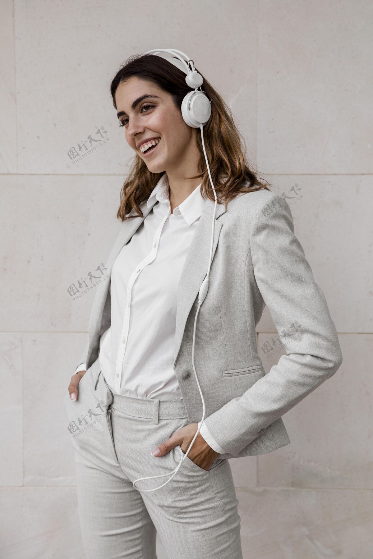 企业家优雅的女商人在耳机上听音乐的前视图行政人员音乐个人