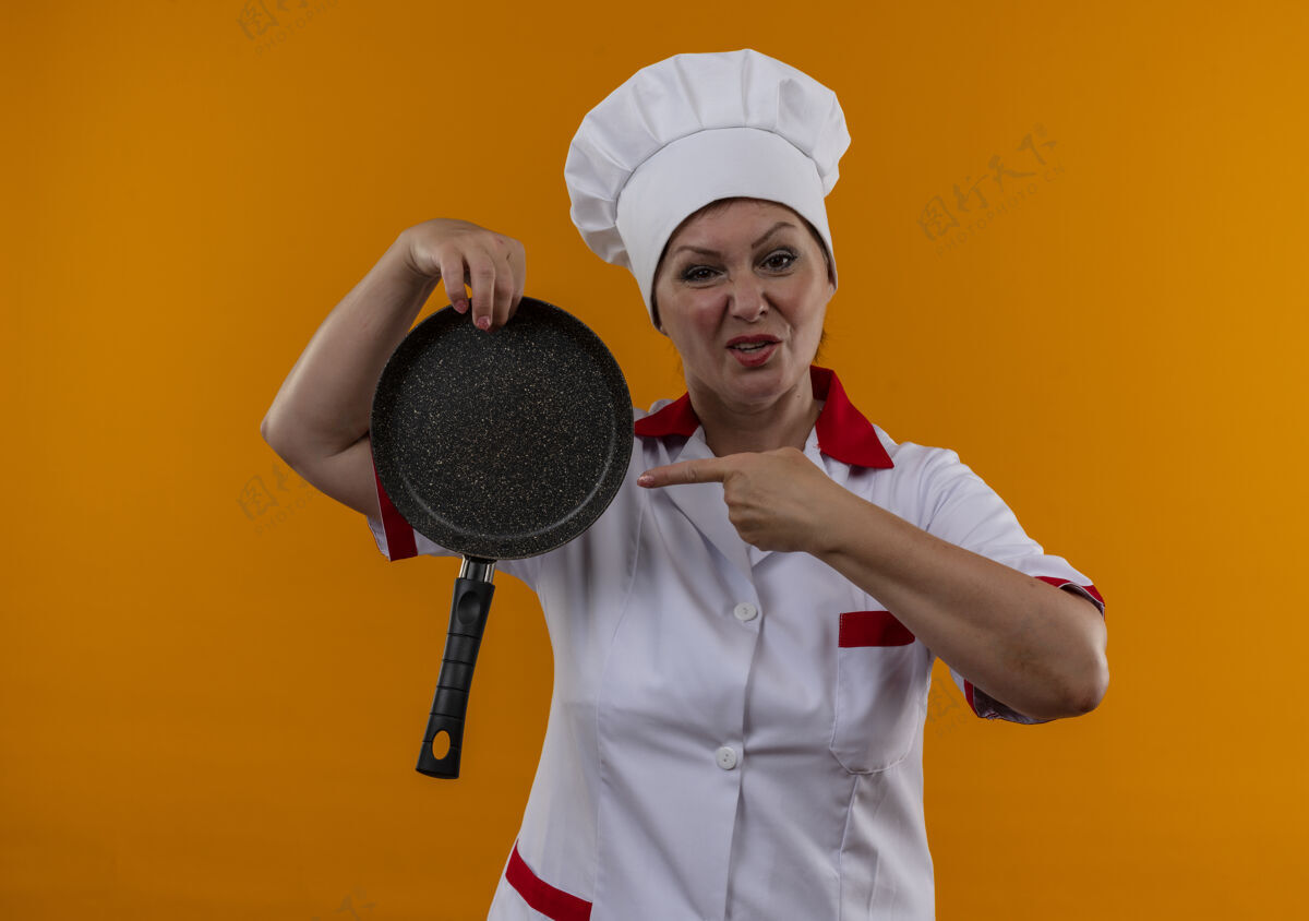 手指穿着厨师制服的中年女厨师指着手中的煎锅未出租厨师点